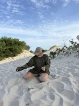 Buzo de manga larga color verde militar, corte oversize, con cuello redondo y pespuntes en contraste color rosa pálido. Presenta un pequeño bordado con la letra "K." en color rosa en el pecho.