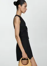 Vestido negro sin mangas con escote en V y detalle de lazo en la parte frontal.