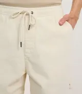 Bermuda de terciopelo color crema, corte runner, con cintura elástica, cordón ajustable y bolsillos laterales.