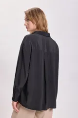 Camisa negra de manga larga con cuello clásico y cierre frontal con botones.