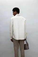 Pantalón jogger de vestir color beige, corte slim fit, con cintura elástica ajustable con cordón, pliegues delanteros y traseros, bolsillos laterales al bies y bolsillos traseros insertados.