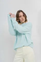 Sweater de punto color celeste, de corte amplio, con escote redondo y puños ajustados.