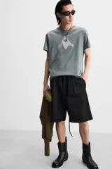 Camiseta gris con efecto lavado, corte relaxed fit, cuello redondo y manga corta. Estampado frontal de una mosca en color blanco.