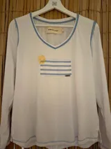 Remera blanca de manga larga con escote en V y vivos celestes en cuello y puños. Estampado en el frente con un sol amarillo y un diseño rectangular con rayas horizontales celestes.