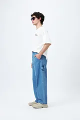 Pantalón jean negro de corte amplio y estilo carpenter, con tiro medio, bolsillos utilitarios y presillas laterales.