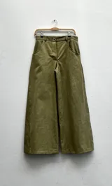 Pantalón de algodón color durazno, de silueta amplia y tiro alto, con diseño de triángulo en los laterales y cierre frontal con botones visibles.