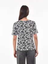 Remera de manga corta con estampado abstracto en tonos beige, negro y blanco.