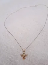 Cadena plateada con dije dorado en forma de paloma con incrustaciones de strass.