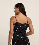 Musculosa de pijama confeccionada en microfibra color negro con estampa de lunares y perritos blancos. Tiene breteles finos fijos y picueta en el escote.