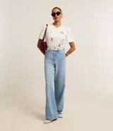 Remera blanca de algodón con cuello redondo y mangas cortas abullonadas. Presenta estampados de un lazo, una flor, un corazón y frases caligráficas.