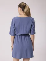 Vestido corto blanco de algodón y lino, con escote en V, mangas cortas y cintura elastizada. Cierre frontal con botones.