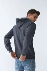 Buzo canguro color arena de felpa, con capucha ajustable, bolsillo tipo canguro, mangas largas y logo estampado en el pecho.