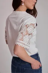 Remera blanca de algodón con mangas cortas de encaje floral.