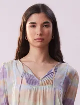 Blusa de gasa estampada con cuello a la base, escote en V plisado y lazo de ajuste. Delantera con detalles en puntilla y manga corta con puño fruncido.