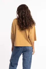 Remera blanca de corte cuadrado con cuello subido y mangas 3/4 amplias.