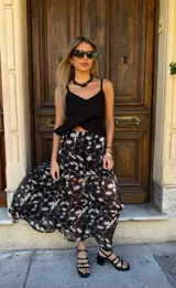 Falda larga de tela estampada con motivos florales en tonos marrones, negros y violetas. Tiene elástico en la cintura y corte acampanado.