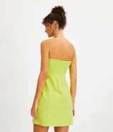 Vestido corto sin breteles color verde lima, confeccionado en lino y algodón. Presenta bolsillos laterales y bordado frontal de una palmera y conchas marinas.