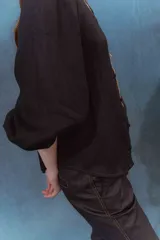 Camisa negra de lino con cuello mao, mangas abullonadas con elástico en los puños y botones forrados en la misma tela.