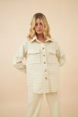 Camisa estilo leñador color beige con textura de espiga, de manga larga con puños abotonados, cuello clásico, cierre frontal con botones y dos bolsillos de parche con solapa abotonada en el pecho.
