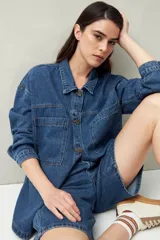 Sobrecamisa oversize de jean azul con cuello camisero, cierre frontal con botones, mangas largas y bolsillos de parche en el pecho.