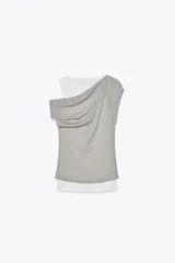 Camiseta blanca con musculosa gris superpuesta con escote asimétrico.