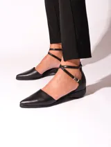Zapato de cuero negro con punta fina y tira con hebilla alrededor del tobillo.