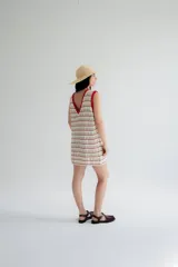 Vestido corto tejido a crochet color marrón con rayas horizontales blancas y cuello y sisas con borde rojo.