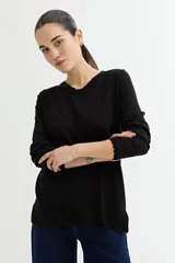 Sweater negro de tejido de punto con cuello redondo y terminaciones con detalle de crochet. De manga larga y corte recto.