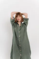 Vestido camisero midi color verde militar, de lino 100%, con silueta oversize, cuello camisero, mangas 3/4 con botón para ajustar y aberturas laterales.