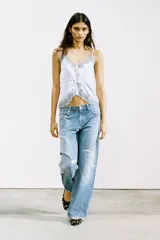 Jeans de denim celeste lavado, corte boyfriend ancho, tiro medio, con roturas y apliques/bordados en forma de corazón en diferentes partes de las piernas.