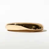 Brazalete rígido dorado con forma ovalada.