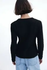 Saco negro en tejido bouclé con cuello redondo, botones forrados hasta la cintura y corte acampanado en la parte inferior.