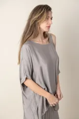 Blusa italiana gris de viscosa, lisa, con corte irregular y un hombro descubierto. De calce holgado.