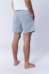 Short de baño celeste con rayas verticales blancas.