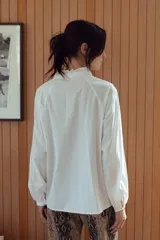Camisa de manga larga con cuello mao y escote en V, a rayas verticales azules y blancas con detalle de puntilla blanca en el canesú.