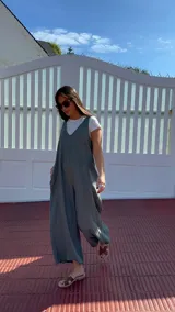 Mono largo de lino color beige, con breteles finos ajustables que se atan en la espalda, corte holgado y bolsillos laterales.