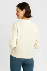 Sweater color crema de poliéster, corte relaxed y cuello en V.