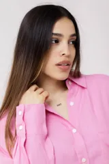 Camisa blanca de lino, de corte holgado, con cuello clásico, cierre frontal con botones, bolsillo en el pecho y mangas largas con puños abotonados.