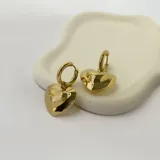 Par de aros dorados de acero quirúrgico hipoalergénico con baño en oro 18k. El diseño consiste en un aro tipo argolla del que cuelga un dije con forma de corazón inflado.