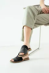 Sandalias de cuero negras con diseño de tiras cruzadas y detalle de elástico en el talón.