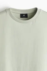 Remera verde claro de algodón, corte estándar, con cuello redondo ribeteado y bajo recto.