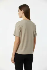 Remera de algodón negra, manga corta y cuello redondo, con un diseño abstracto de líneas curvas formadas por apliques de studs plateados en el pecho.