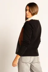 Campera negra con paneles de cuero color marrón, mangas largas de tejido de punto y cuello de piel sintética color crema.