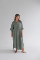 Camisola larga verde con rayas verticales blancas, confeccionada en lino. Tiene cuello camisero, mangas 3/4 con botón ajustable y cierre frontal con botones.