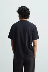 Camiseta blanca de algodón de peso medio, corte recto, cuello redondo y mangas cortas.