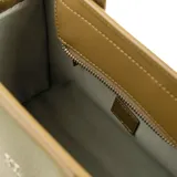 Cartera tipo tote de cuero sintético graneado color verde oliva, con doble asa de mano y correa bandolera ajustable y desmontable. Tiene cierre superior, herrajes plateados y logo metálico XL en el frente. El interior es de tela de algodón y poliéster, con dos bolsillos abiertos y uno con cierre.