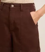 Short de mujer de sarga color beige claro, tiro alto, con pespuntes contrastantes en color blanco o crema. Presenta un corte regular y bolsillos delanteros y traseros.