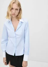 Camisa celeste de popelina de algodón con cuello y puños blancos en contraste, manga larga con puños abotonados, corte recto, cierre delantero con botones y diseño entallado.