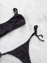 Conjunto de bikini con estampado a cuadros azul y blanco, compuesto por un corpiño bandeau con breteles regulables y una bombacha vedetina con tiras laterales para atar.