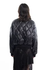 Campera bomber negra de tela satinada con cierre frontal, cuello redondo y puños y cintura elastizados. Tiene un pequeño logo bordado en el pecho y un bolsillo con cierre en la manga. Es reversible.